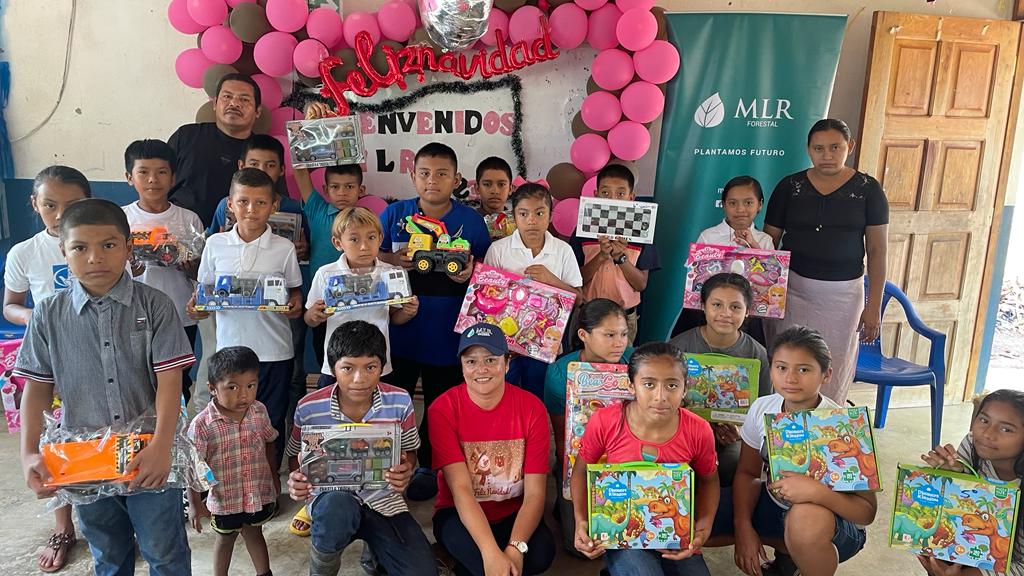 Children from the San Francisco de Asís school in the San Miguel community pose with their toys and the welcome poster they made for the company.